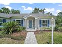 Inviting front entrance with a blue door, elegant landscaping, and brick pathway at 809 Northside Dr, Mount Dora, FL 32757