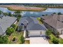 Aerial view of a beautifully landscaped home with a large driveway and stunning views of a tranquil lake at 8664 Bridgeport Bay Cir, Mount Dora, FL 32757