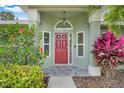 Red front door with decorative plants, tiled floor and sidelight windows, covered porch at 8709 Augusta Ct, Clermont, FL 34711
