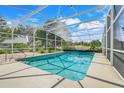 Screened-in pool with ample deck space and string lights; golf course and landscaping in background at 8709 Augusta Ct, Clermont, FL 34711