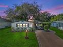 Charming home exterior at dusk with lush green lawn and inviting carport area at 941 Tarrson Blvd, Lady Lake, FL 32159