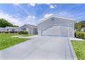 Driveway view showcasing a two-car garage and the well manicured lawn at 9461 Se 173Rd Ln, Summerfield, FL 34491
