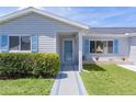 Inviting front entrance with blue trimmed glass door, manicured bushes and blue shutters at 9461 Se 173Rd Ln, Summerfield, FL 34491