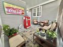 Relaxing porch area with comfortable wicker furniture, fun coca cola theming, and plants at 102 Dogwood Trl, Leesburg, FL 34748
