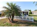 Front exterior with a mature palm tree and a white picket fence at 1070 Pinewood Pl, The Villages, FL 32162
