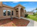 A well-maintained beige house with an arched front door and lush landscaping at 13336 Biscayne Dr, Grand Island, FL 32735
