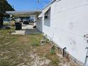 Side view of a modest single-story home with covered parking and sparse landscaping at 1425 County Dr, Tavares, FL 32778