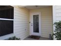Inviting front entryway with decorative glass door and neutral siding, enhanced by lush landscaping at 1482 Azteca Loop, The Villages, FL 32162