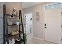 Inviting foyer with neutral color palette, decorative tile flooring, a modern shelf and a view of the laundry room at 1548 Planters Point Rd, Kissimmee, FL 34744