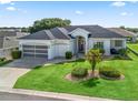 Beautiful single-story home with well-manicured lawn, mature landscaping, and two-car garage on a sunny day at 17471 Se 110Th Ter, Summerfield, FL 34491
