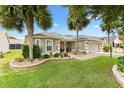 A lovely home showcasing a well-kept lawn, lush trees, and a charming front patio area at 2015 Palo Alto Ave, The Villages, FL 32159