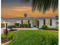 Charming single-story home features a manicured lawn, mature landscaping, and a concrete driveway with a unique design at sunset at 2022 Claudio Ln, The Villages, FL 32159