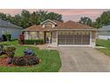 Charming single-story home at dusk, featuring a manicured lawn, mature trees, and a two-car garage at 22217 Caledonia Dr, Leesburg, FL 34748