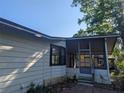 A quaint home showcasing a screened porch and a meticulously maintained exterior with lush landscaping at 2871 Myakka River Rd, Tavares, FL 32778
