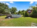 Spacious backyard featuring an above ground pool, mature trees, and a charming red barn at the edge of the property at 28924 Discovery Rd, Tavares, FL 32778