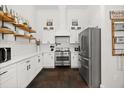 Modern kitchen with stainless appliances, white cabinetry, subway tile backsplash, floating shelves and dark stone flooring at 28924 Discovery Rd, Tavares, FL 32778