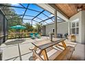 Expansive screened patio with ample seating, a picnic table, string lights, and a view of the private backyard at 28924 Discovery Rd, Tavares, FL 32778
