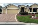 Charming single-story home boasts a two-car garage and a brick-paved driveway, complemented by lush landscaping at 3319 Barrington Ct, The Villages, FL 32162