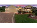 Inviting single-story home featuring a well-manicured lawn and a brick-paved driveway leading to a two-car garage at 3319 Barrington Ct, The Villages, FL 32162