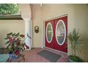 A close up shot of the red, double front door with oval glass inserts, framed by a white column at 35350 County Road 439, Eustis, FL 32726
