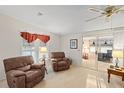 Spacious living room featuring plush armchairs, carpet and sliding glass doors at 522 Saint Andrews Blvd, Lady Lake, FL 32159