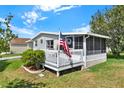 View of a home featuring a porch with an American Flag, a small garden and green lawn on a sunny day at 741 Royal Palm Ave, Lady Lake, FL 32159