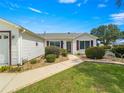 Inviting home exterior with well-kept lawn, elegant landscaping, and a cozy bench at 8069 Se 174Th Ludlow Pl, The Villages, FL 32162