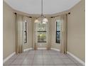 Bright dining area featuring tile floors, three windows with curtains and a hanging chandelier at 8167 Bridgeport Bay Cir, Mount Dora, FL 32757