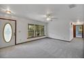 Bright living room featuring plush carpeting, a ceiling fan, fresh white walls, and natural light from a window at 9236 County Road 48, Yalaha, FL 34797