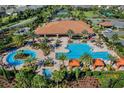Aerial view of the community pool with palm trees, lounge chairs, and a hot tub at 1027 Timbervale Trl, Clermont, FL 34715