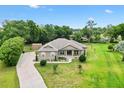 Sprawling property featuring a well-maintained home, lush greenery, an outbuilding, and a long driveway at 10465 Se 41St Ter, Belleview, FL 34420