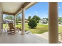 Inviting front porch with classic rocking chairs and columns, offering a peaceful view of the surrounding landscape at 10465 Se 41St Ter, Belleview, FL 34420