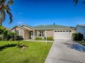 Well-maintained single-story home featuring an attached garage, and a green lawn in a quiet neighborhood at 1060 Davenport Dr, The Villages, FL 32162