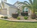Well-kept front yard features lush lawn and landscaping with flowers, shrubs, and a mature palm tree at 11277 Se 170Th Ln, Summerfield, FL 34491