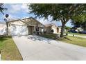 Inviting one-story home with well manicured lawn, long driveway, and an attached two-car garage at 12430 Ne 52Nd Loop, Oxford, FL 34484