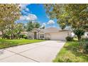 Inviting home with a long driveway and an attached two-car garage, surrounded by mature trees and manicured lawn at 12512 Lake Ridge Cir, Clermont, FL 34711
