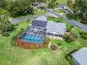 Aerial view of a residence with a screened pool, well-manicured landscaping, and a solar-paneled roof at 17819 Se 105Th Ct, Summerfield, FL 34491