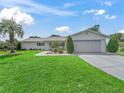Inviting single-story home featuring a manicured lawn, mature landscaping, and an attached two-car garage at 17819 Se 105Th Ct, Summerfield, FL 34491