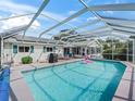 Screened-in pool with clear water, outdoor seating, and white house in background at 17819 Se 105Th Ct, Summerfield, FL 34491