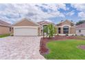 Charming single-story home boasts a well-manicured lawn, brick driveway, and attached two-car garage at 1972 Palo Alto Ave, The Villages, FL 32159