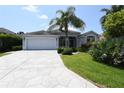 Charming single-story home featuring a spacious driveway, lush landscaping, and a welcoming two-car garage at 2120 Willow Grove Way, The Villages, FL 32162
