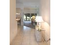 Inviting hallway featuring tile flooring, decorative lamps, and a glimpse into the bright and airy living spaces at 2120 Willow Grove Way, The Villages, FL 32162