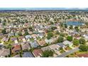 Wide aerial shot of a dense neighborhood with houses, streets, trees, and a small body of water in the distance at 2202 Kershaw Rd, The Villages, FL 32162