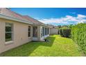 A well-maintained backyard featuring green grass, a screen enclosed back porch, and lush hedges creating a private outdoor space at 2202 Kershaw Rd, The Villages, FL 32162
