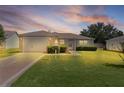 Charming single-story home featuring a well-manicured lawn and attached one car garage at dusk at 2369 Five Forks Trl, The Villages, FL 32162