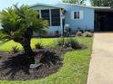 Side view of a blue single-story home, green grass and plantings at 24841 Pine Hl, Leesburg, FL 34748