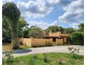Inviting view of a Spanish-style home with a stucco facade, surrounded by lush greenery and mature trees at 308 Sunnyside Dr, Leesburg, FL 34748