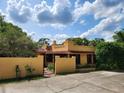 Charming Spanish-style home with a stucco exterior, red tile roof, gated entry, and well-manicured landscaping at 308 Sunnyside Dr, Leesburg, FL 34748