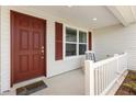 Welcoming front porch with a red door, white railings, and a comfortable chair at 3118 Sweetgum St, The Villages, FL 32163