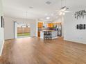 Bright living room with wood floors, ceiling fan, and kitchen view with a large sliding glass door at 3118 Sweetgum St, The Villages, FL 32163